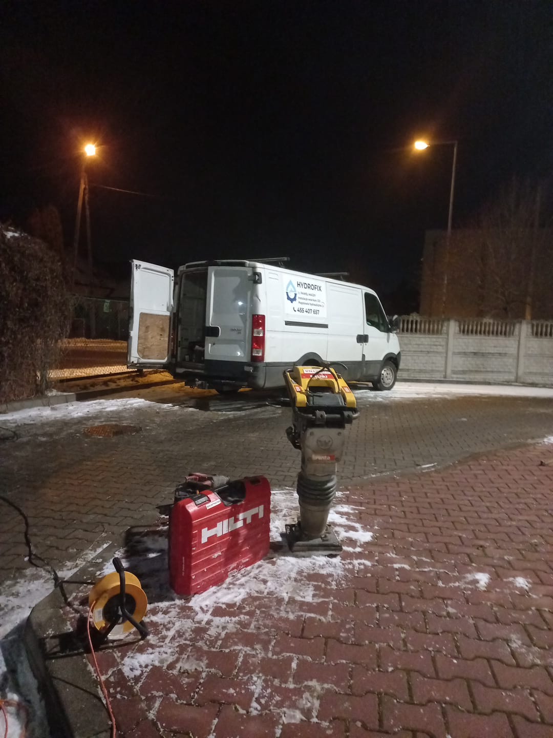 Samochód dostawczy z otwartymi drzwiami i sprzętem budowlanym na zewnątrz.
