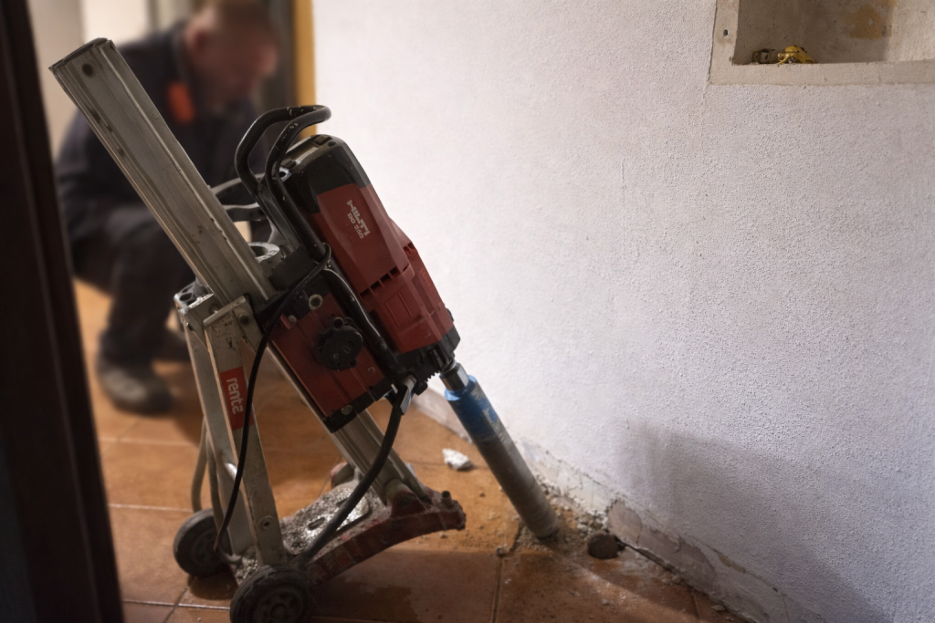 Wibrator do betonu przy ścianie, mężczyzna w tle.